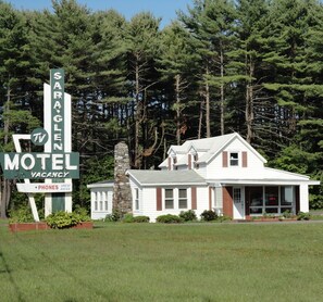 A motel with a stone chimney, a TV sign, and a sign indicating vacancy. - Sara Glen Motel (Fort Edward)