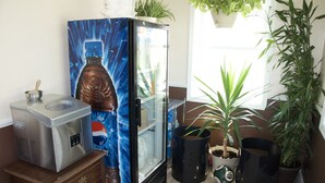 A kitchen with a refrigerator, a microwave, and a sink. There are potted plants and a window with natural light.