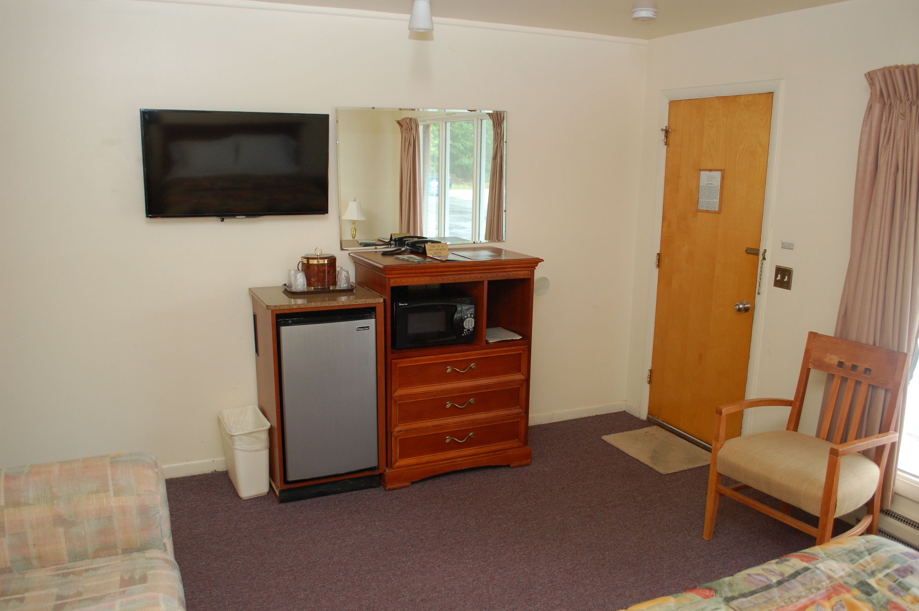 A room with a bed, a desk with a computer, a television, a door, and a chair.