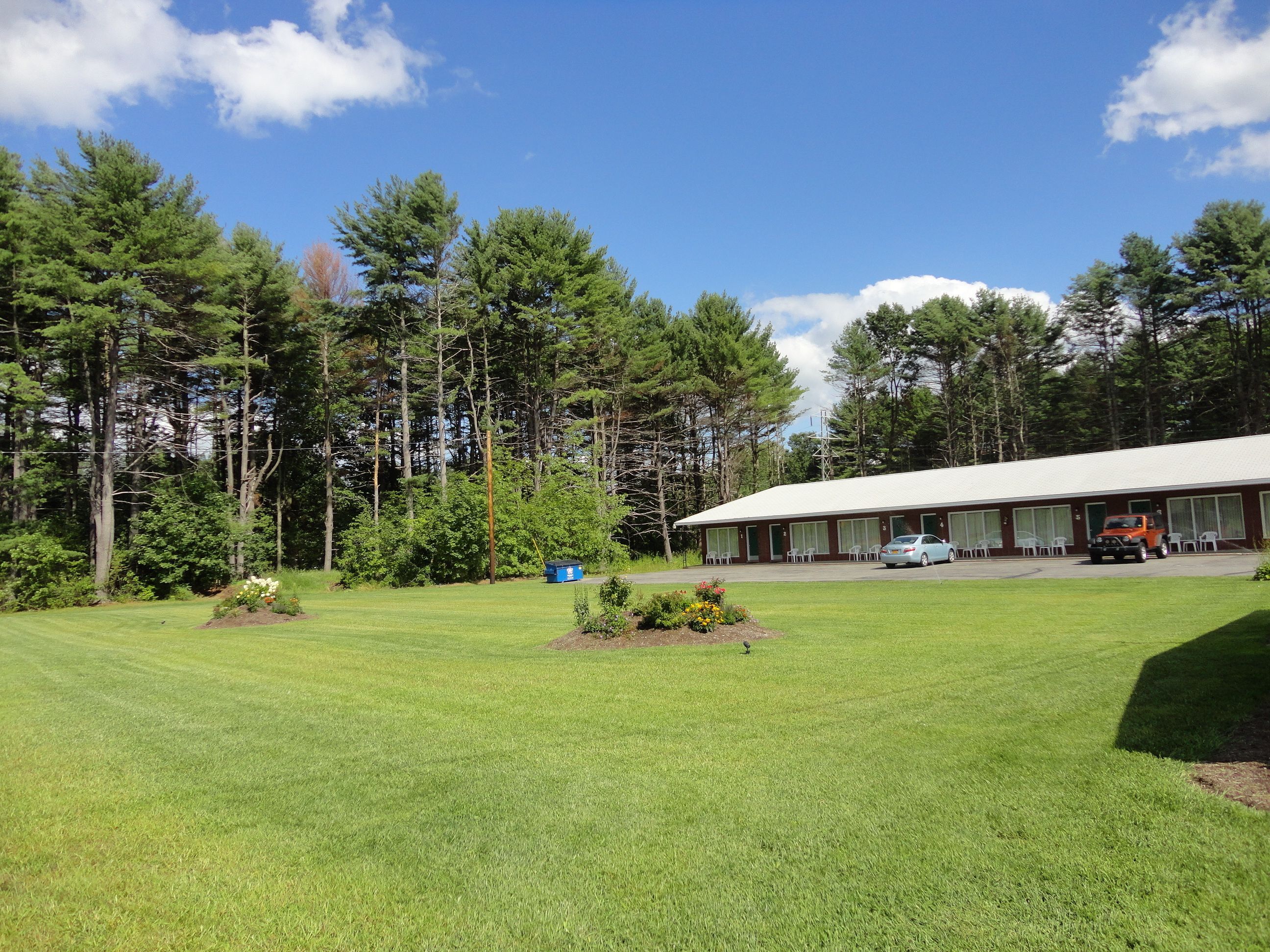 A building with a flat roof, surrounded by a well-maintained lawn and tall trees.