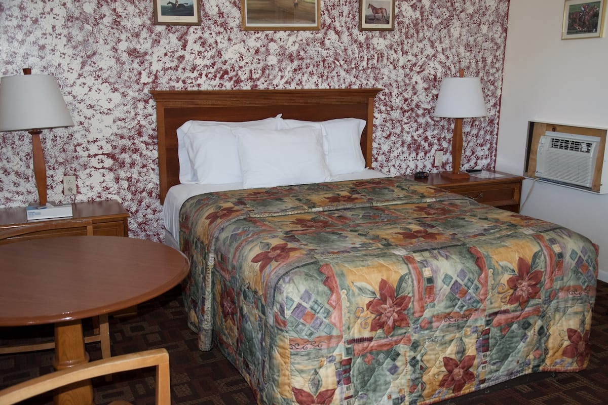 A neatly made bed with a floral comforter, a wooden headboard, and two bedside lamps.