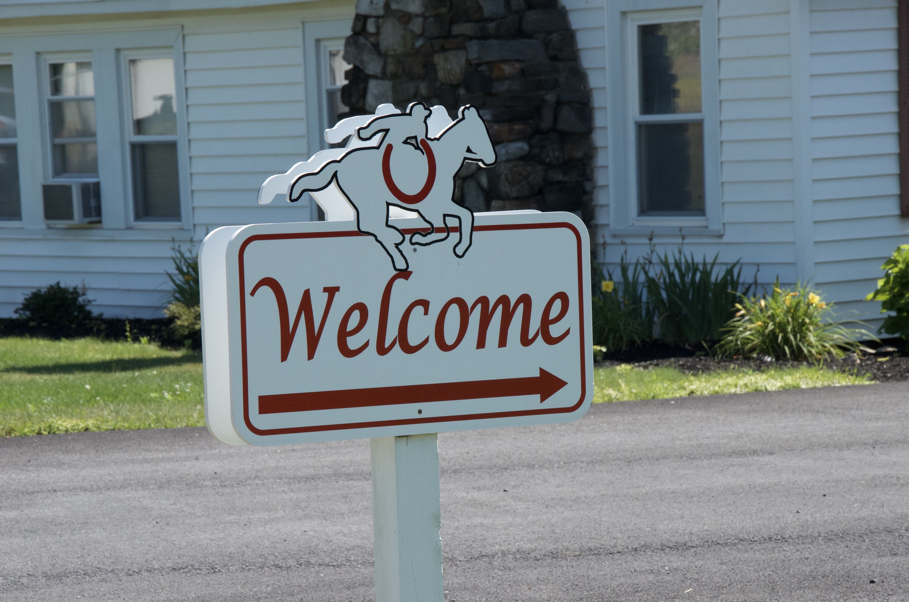 A welcome sign with a horse silhouette and an arrow pointing right.