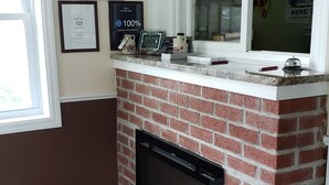 A hotel lobby with a brick fireplace, framed awards on the wall, and a view sign.
