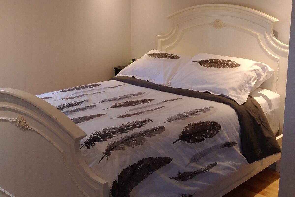 Una cama bien hecha con cabecera blanca y colcha estampada.