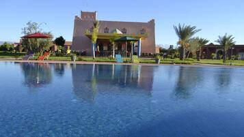 Alberca al aire libre, sombrillas en la alberca y camastros