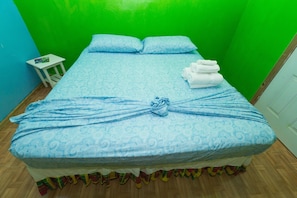 A bed with a blue patterned bedspread, two pillows, and a towel arrangement. - Serenity Escape St Lucia (Soufrière)