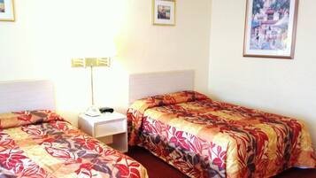 Een hotelkamer met twee enkele bedden, een nachtkastje met een lamp en een lijst aan de muur.