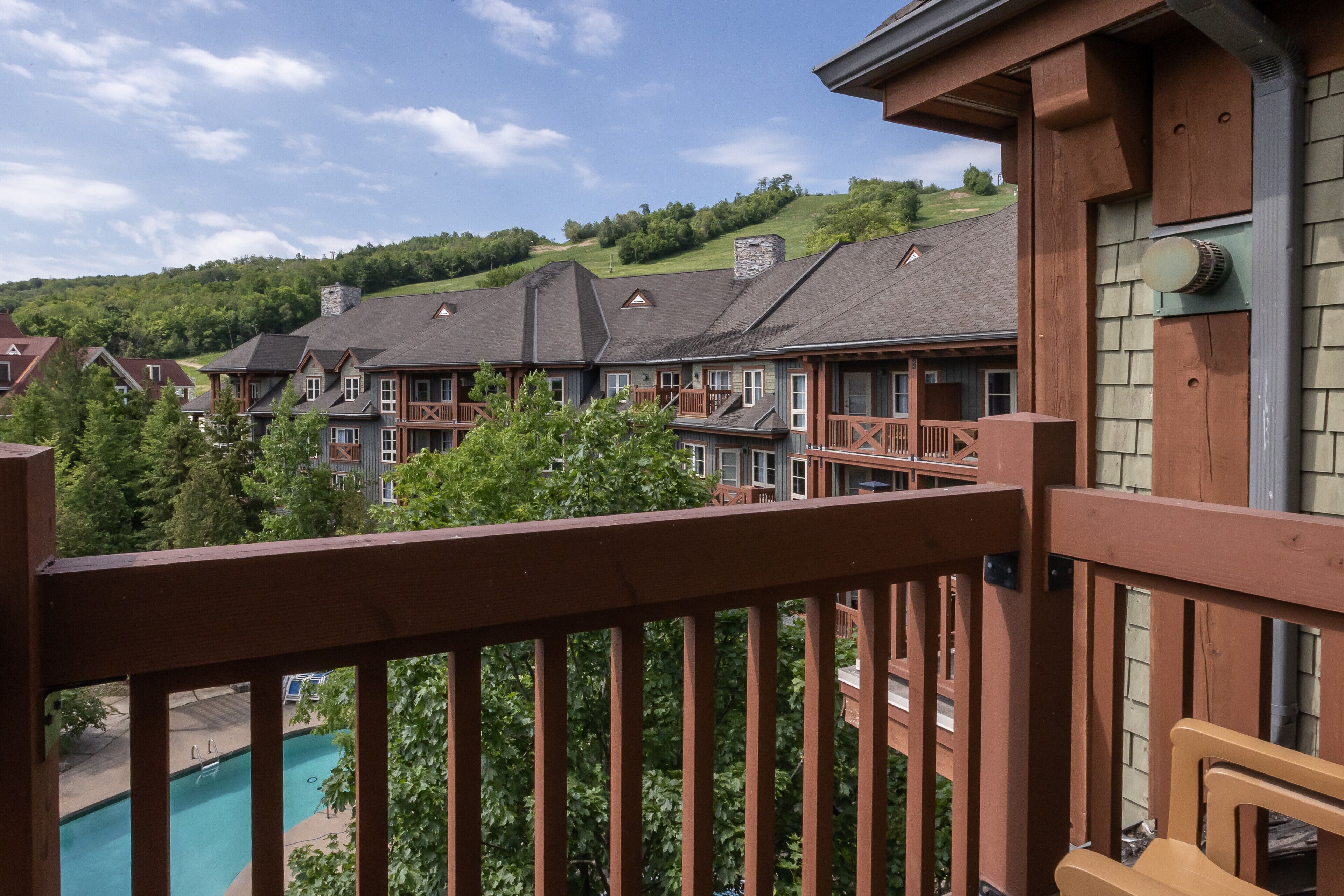 A hotel with multiple buildings, a swimming pool, and a view of a green hillside.