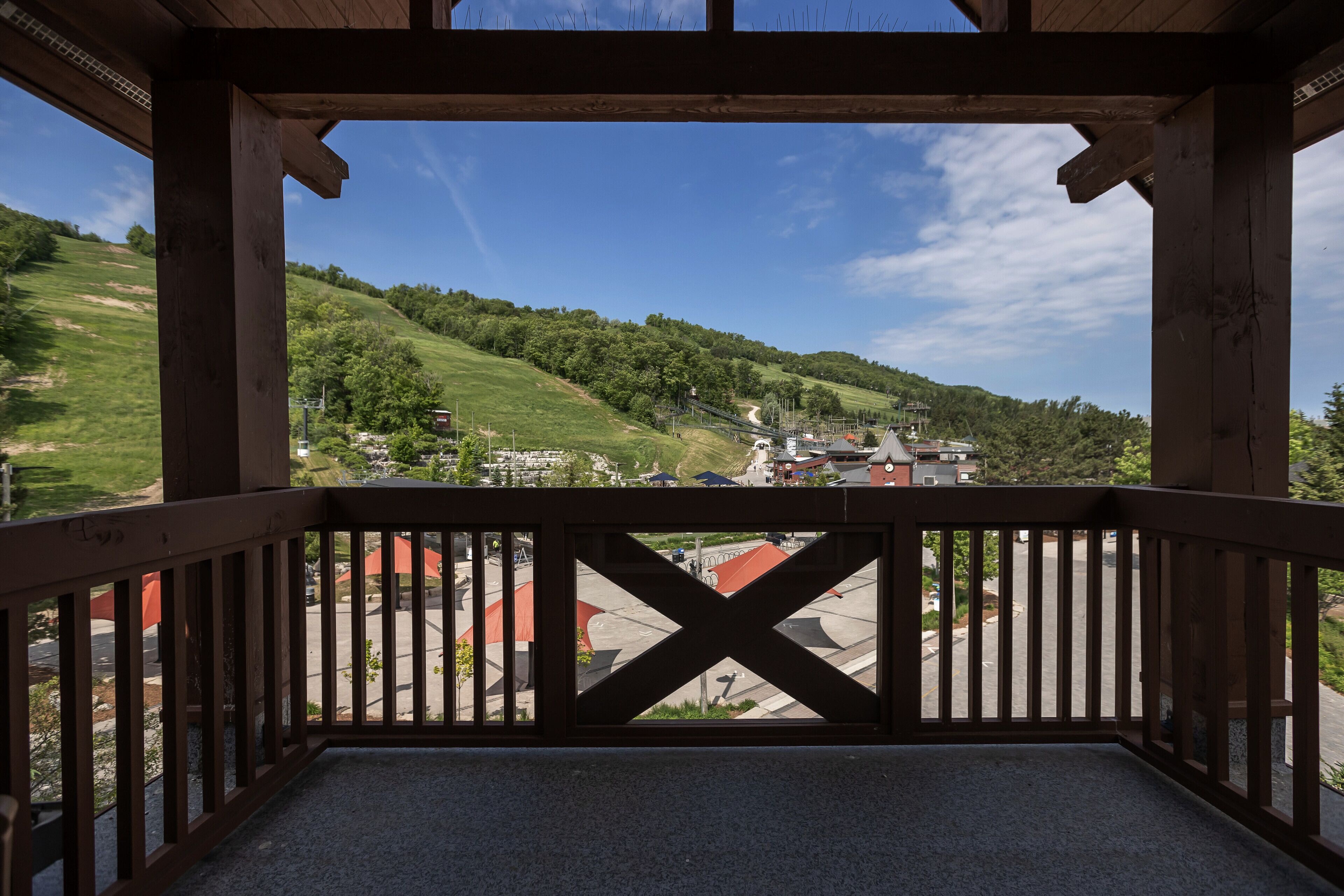 Un balcone in legno che si affaccia su un paesaggio collinare e un piccolo paese sottostante.