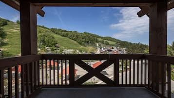 Un balcone in legno che si affaccia su un paesaggio collinare e un piccolo paese sottostante.