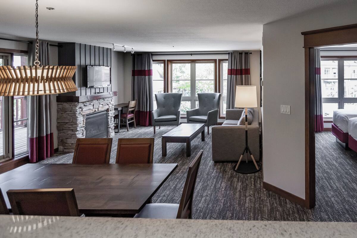 A hotel room with a dining area, a fireplace, a bed, and a view of the outside.