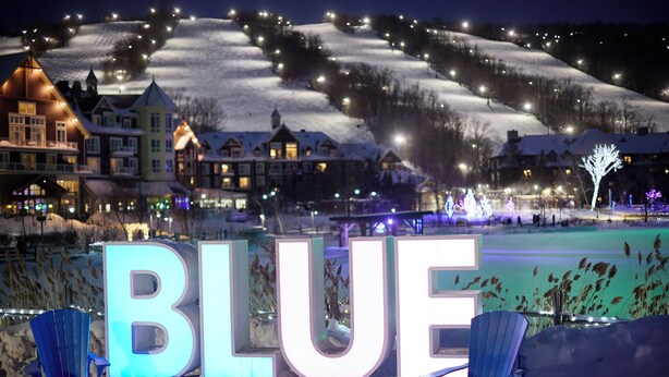 Lumipeitteinen maisema, jossa rakennukset on valaistu ja suuriin kirjaimiin kirjoitettu sana ”BLUE”.