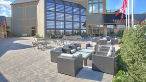 A hotel with outdoor seating, large windows, and flags.
