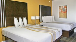 A hotel room with two beds, a nightstand, a lamp, and a painting on the wall. - Palacio Royale Inn Houston NW Beltway 8 (Houston)