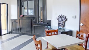 A dining area with a white table and wooden chairs, a dark wooden door, and a glass partition. - Palacio Royale Inn Houston NW Beltway 8 (Houston)