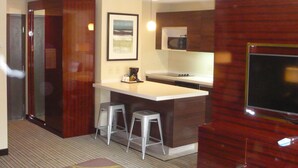 A compact hotel room with a kitchenette, a small bar area, and two bar stools. - Super 8 by Wyndham Copley Akron (Akron)