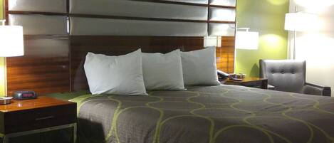 A hotel room with a large bed, two bedside tables, a chair, and a headboard.