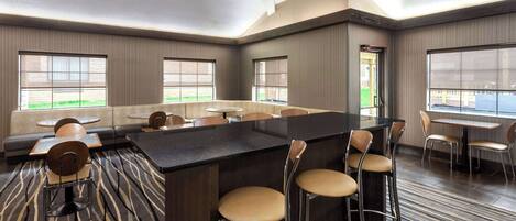 A modern hotel lobby with a central bar area, seating arrangements, and large windows offering views.