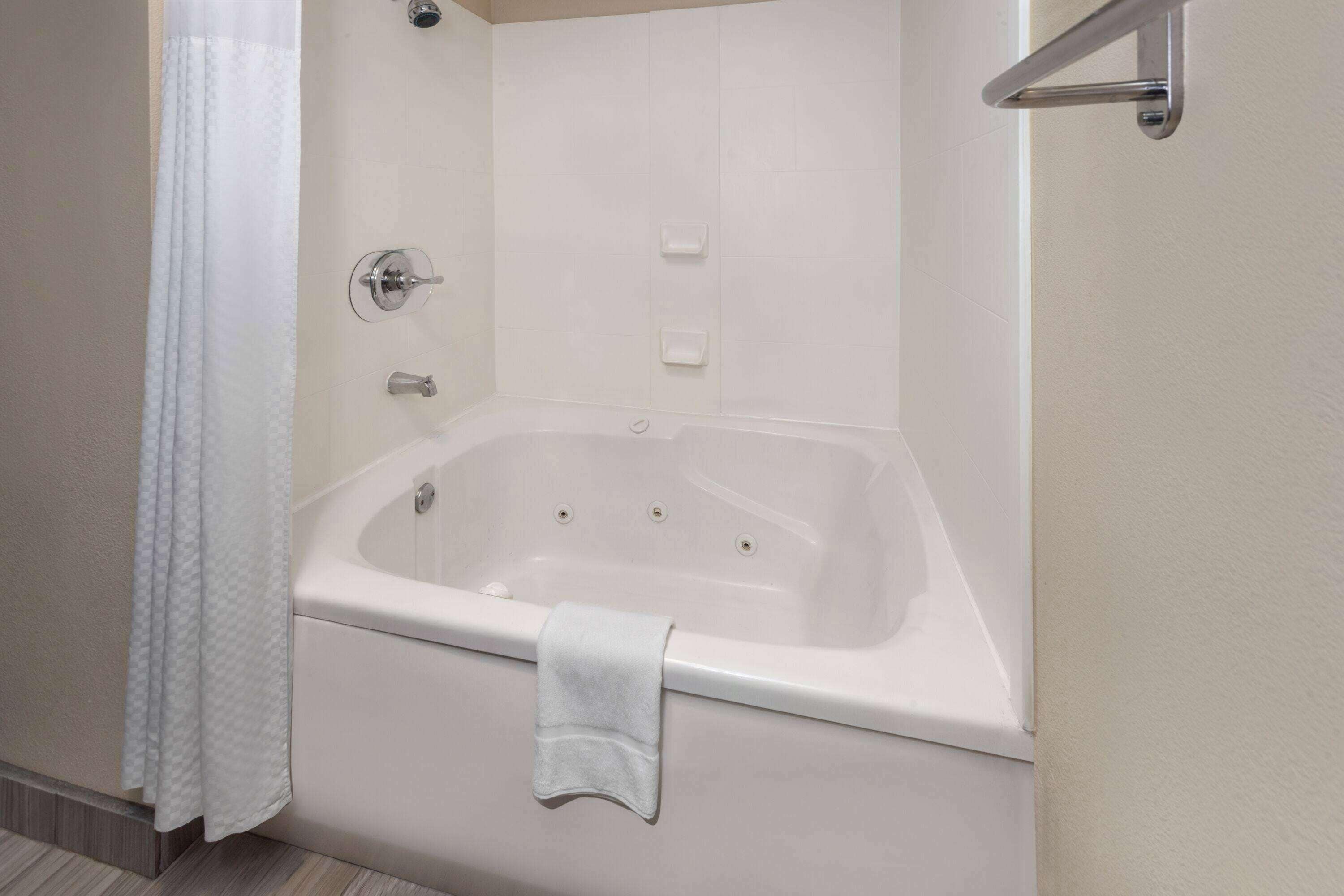 Een moderne badkamer met een vrijstaand bad, een douchegordijn en een handdoekrek.