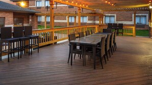 An outdoor deck with a wooden railing, a glass-top table, and multiple chairs. - Super 8 by Wyndham Copley Akron (Akron)