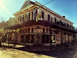 A two-story building with a balcony on the second floor, a sign that reads "Royal Street Inn," and a flag hanging from the balcony.