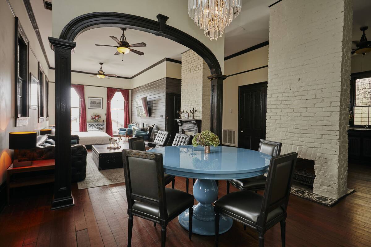 A dining area with a round blue table, black chairs, and a chandelier.