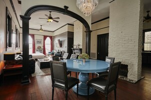 A dining area with a round blue table, black chairs, and a chandelier.