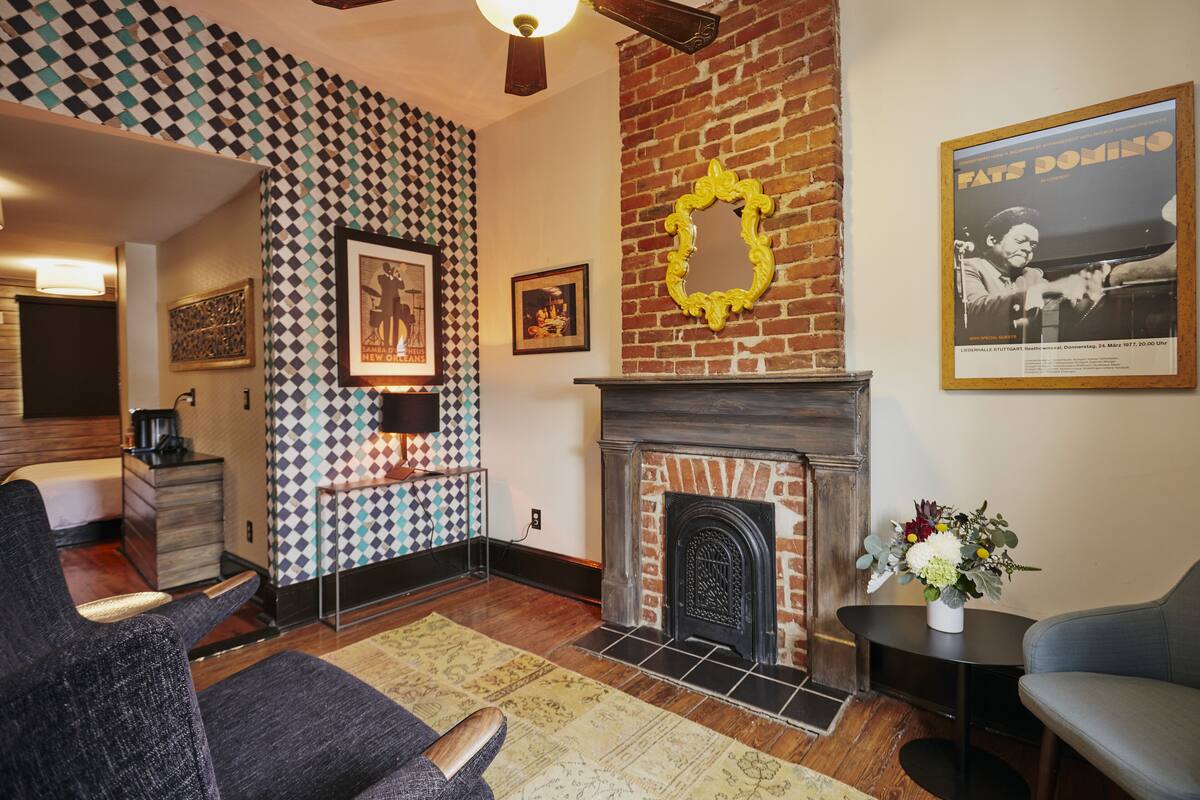 A living room with a fireplace, patterned wallpaper, and a poster on the wall.