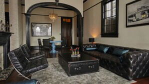 Ein Wohnzimmer mit einem schwarzen Ledersofa, einem blauen Couchtisch und einem Kamin.