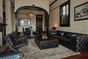 A living room with a black leather sofa, a blue coffee table, and a fireplace.