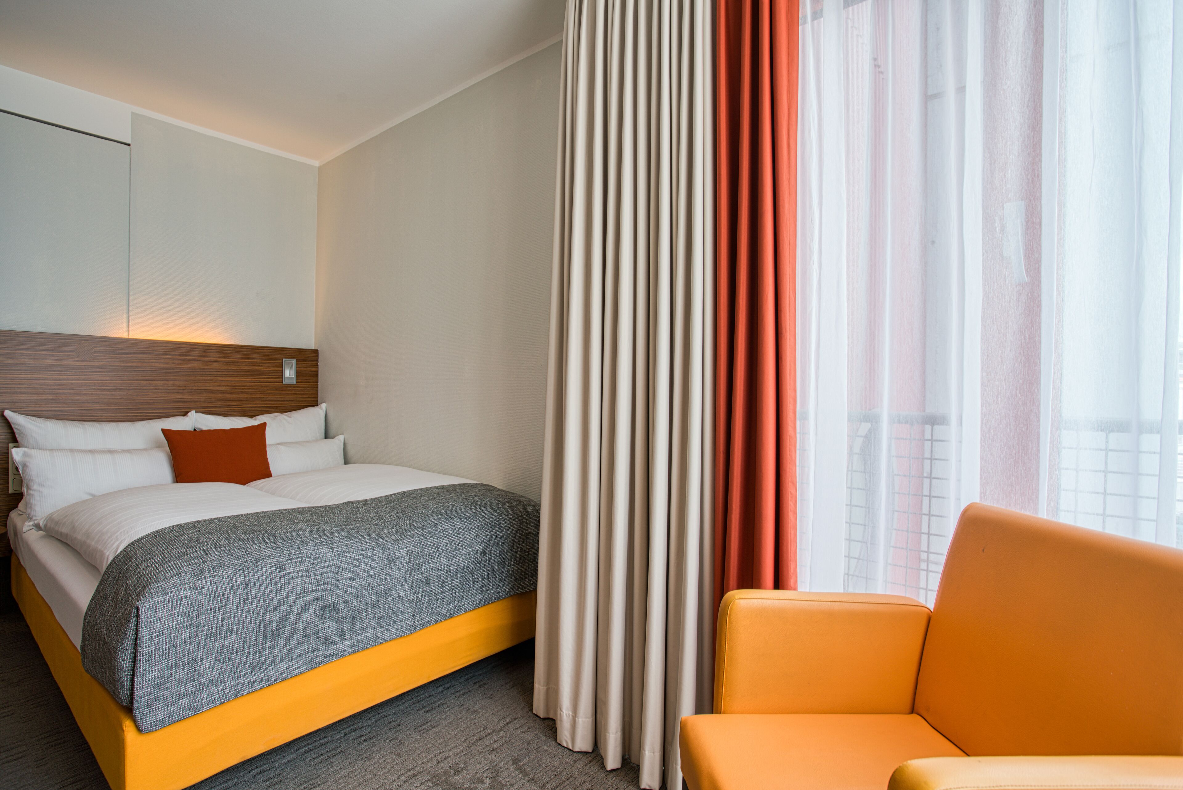 Een hotelkamer met een bed, een stoel en gordijnen.