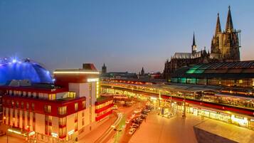 A train station with multiple tracks and a large cathedral in the background.