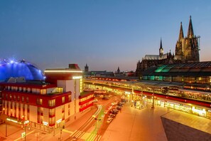 A train station with multiple tracks and a large cathedral in the background. - Kommerzhotel Köln (Cologne)