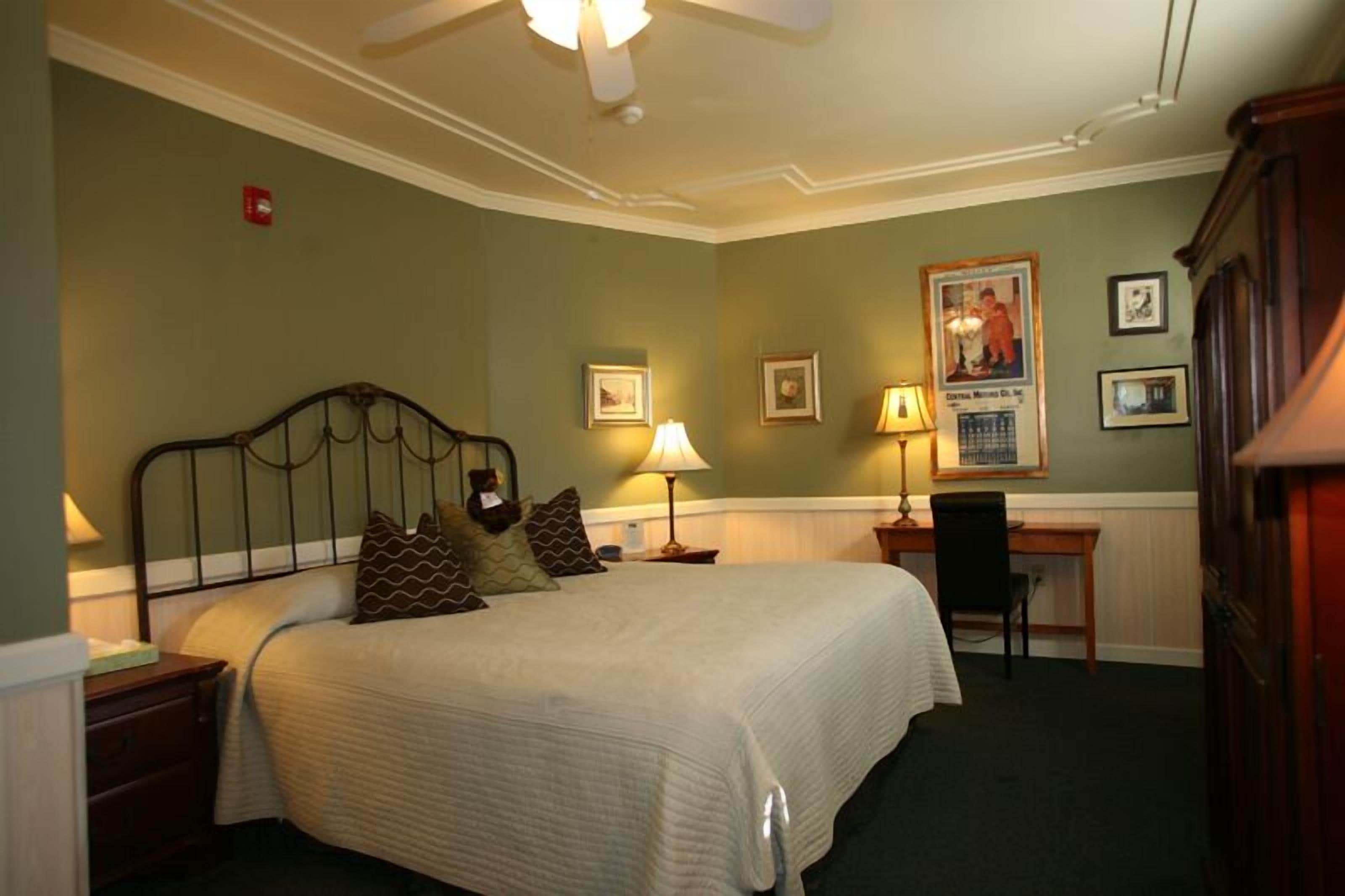 A neatly arranged hotel room with a bed, bedside lamps, a desk, and a chair.