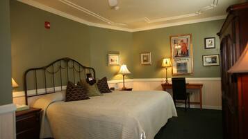 Una habitación de hotel ordenada con cama, lámparas de noche, escritorio y una silla.