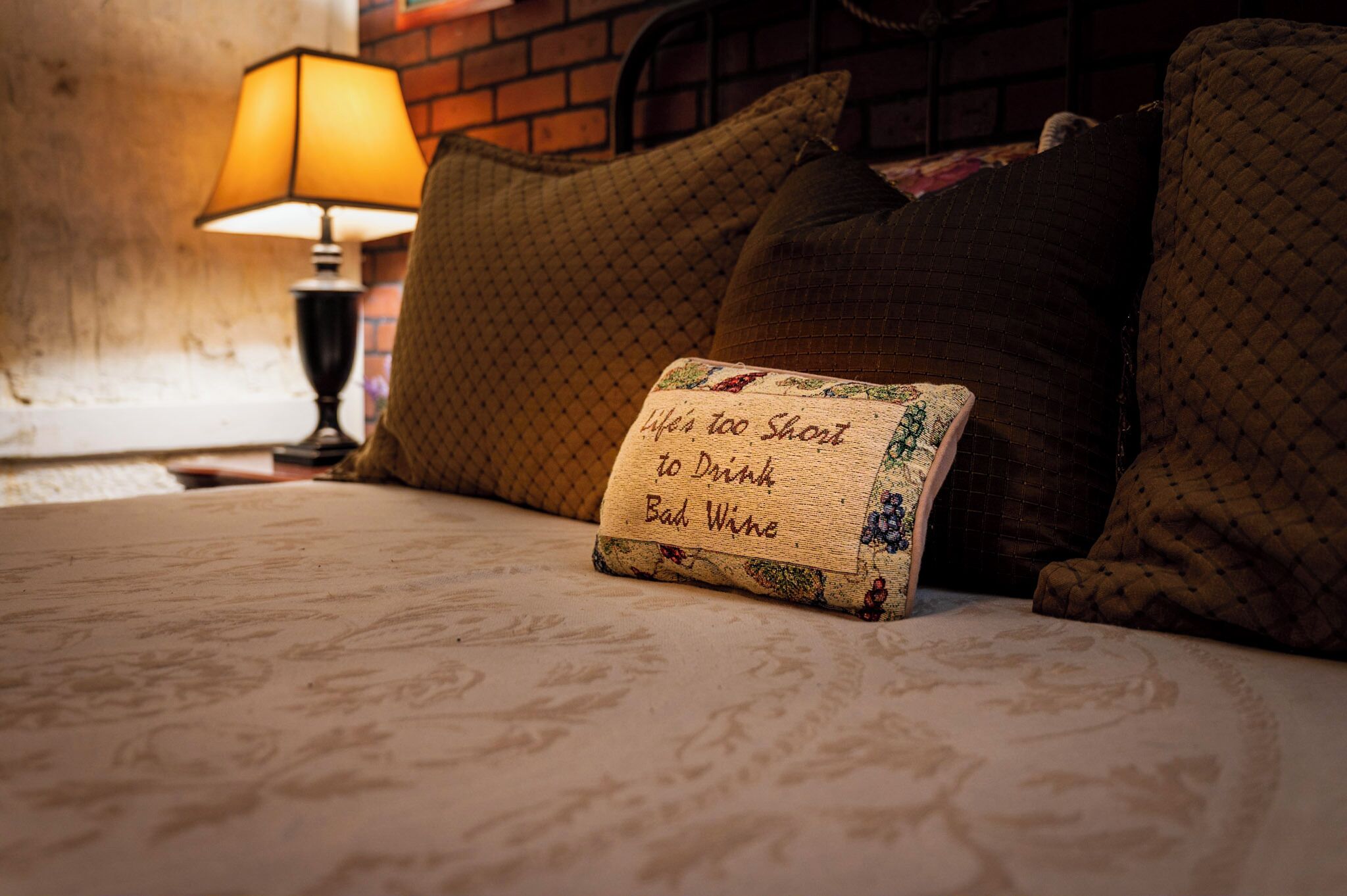 Un letto con un cartello che riporta la scritta 'Life's too short to drink bad wine' e una lampada sullo sfondo.