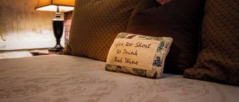 A bed with a sign that reads "Life's too short to drink bad wine" and a lamp in the background.