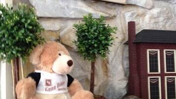 A teddy bear sitting on a stone ledge with a sign above it that reads "Eat Sleep Shop."