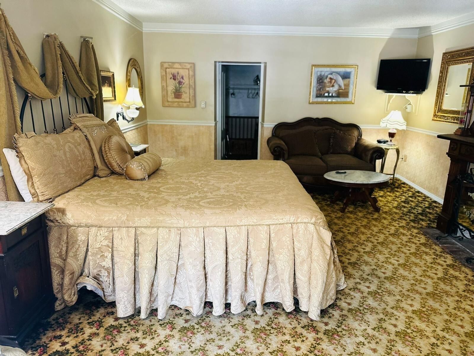A hotel room with a large bed, a sofa, a small table, and a television.