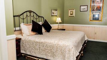 A neatly made bed with a floral bedspread, a nightstand with a lamp, and framed pictures on the wall.