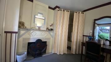A room with a fireplace, a mirror, a chair, and a desk.