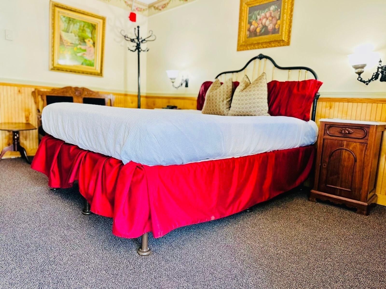 A bed with a red and white bedspread, a wooden headboard, and a small wooden nightstand.