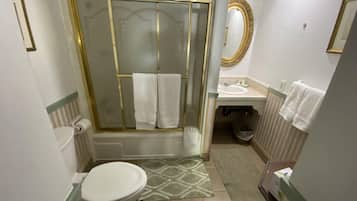 A bathroom with a shower, toilet, sink, and a mirror.