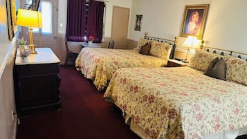 Habitación de hotel con dos camas, un escritorio, una silla, una lámpara y un cuadro en la pared.
