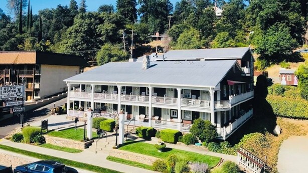 Un hôtel de deux étages doté d’une cour intérieure, d’une piscine et d’une enseigne indiquant « Gunn Hotel, modèle d’auberge historique ».