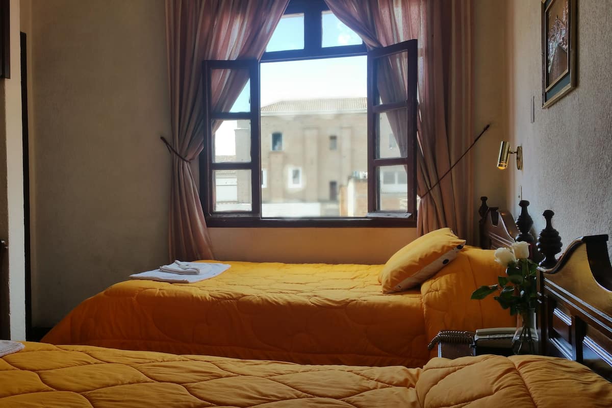 A bedroom with a bed, a window, a bedside table, and a chair.