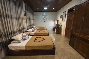 A hotel room with three beds, a wooden wardrobe, a television, and a tiled floor. - MANN Myanmar Inn (Mandalay)