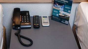 A desk with a landline phone, a cordless phone, a mobile phone, and a brochure.
