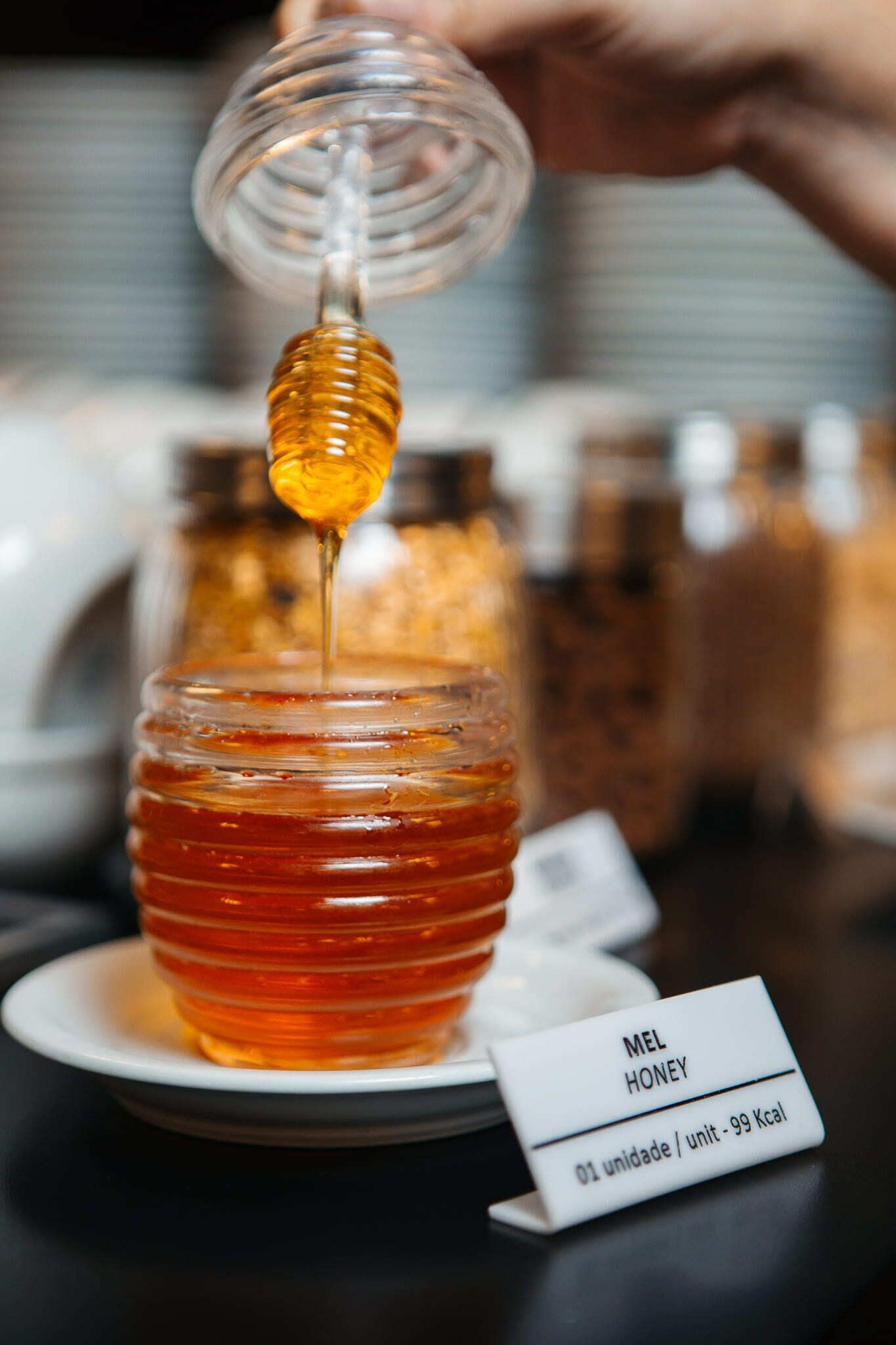 Hunajapurkki, jossa on etiketti, jossa lukee ”MEL HONEY”, ja kyltti, jossa ilmoitetaan: ”01 annos – 99 kcal”.