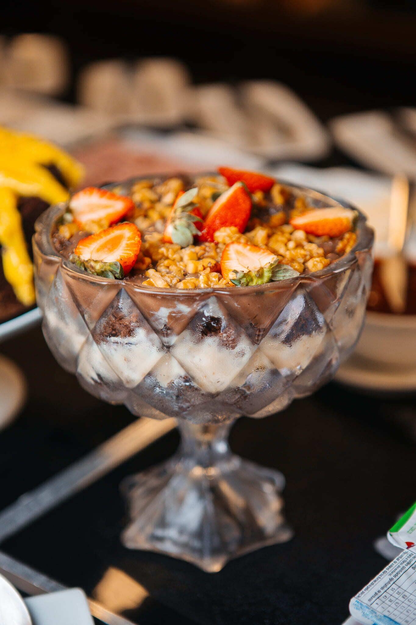 Un dessert in una ciotola di vetro con fragole e granola.